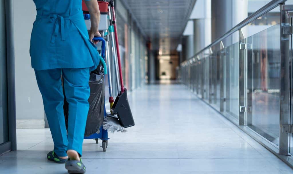 A woman worker in special clothes rolls a trolley for cleaning offices. Cleanroom concept during quarantine.