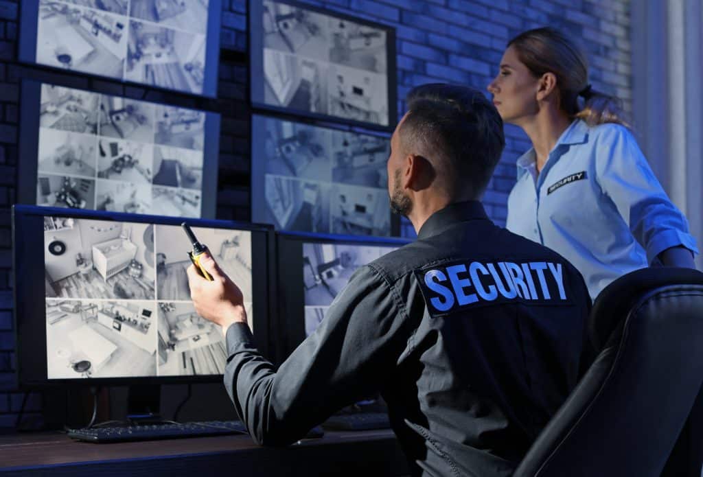 Security guards monitoring modern CCTV cameras indoors