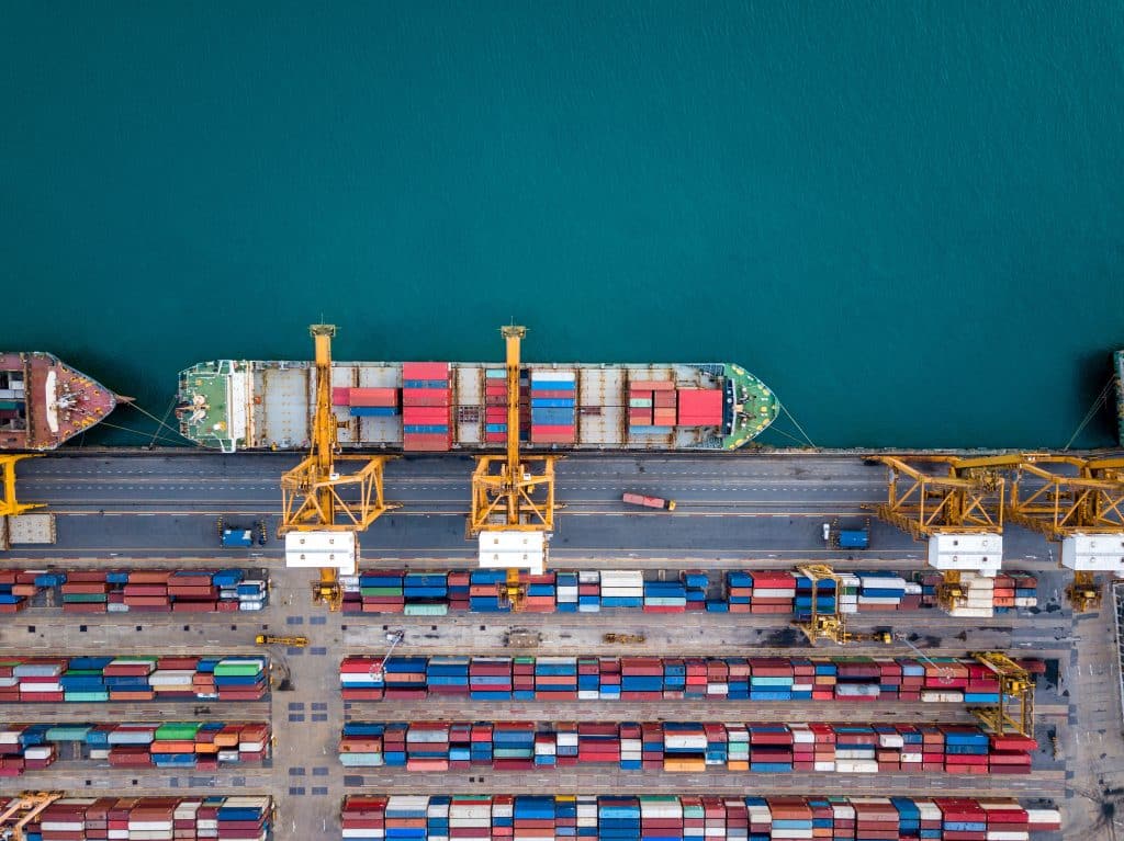 Top view of international port with Crane loading containers in import export business logistics.